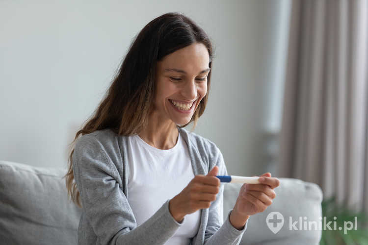 Szczęśliwa kobieta trzyma test ciążowy w dłoniach