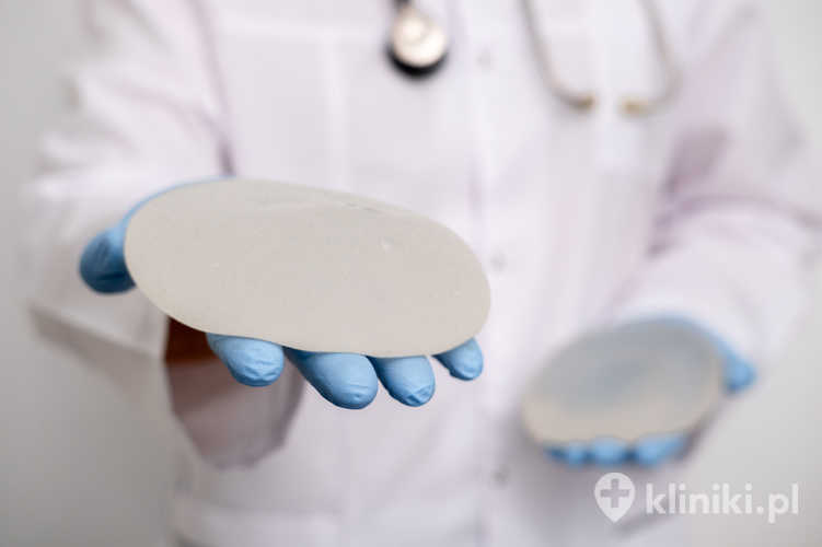 Lekarz trzymający w rękach implant powiększający piersi