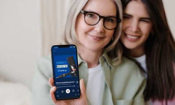 Dwie kobiety i telefon, na którego ekranie widać odcinek podcastu Kliniki.pl
