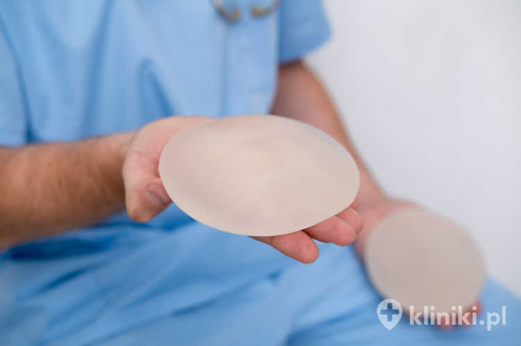 Lekarz trzymający w rękach implant powiększający piersi