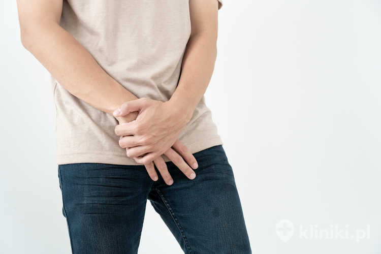 Mężczyzna trzyma rękę przed częściami intymnymi, odczuwając dyskomfort spowodowany zbyt małym penisem