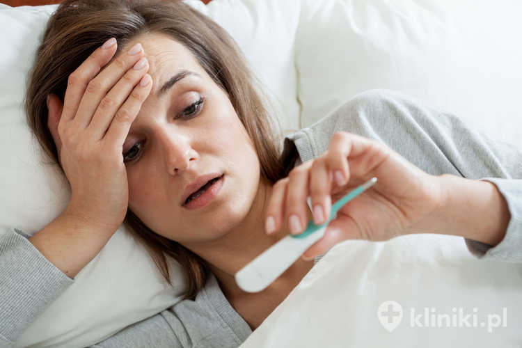 Widok kobiety z gorączką w łóżku - objawy gorączki po podróży w tropikach