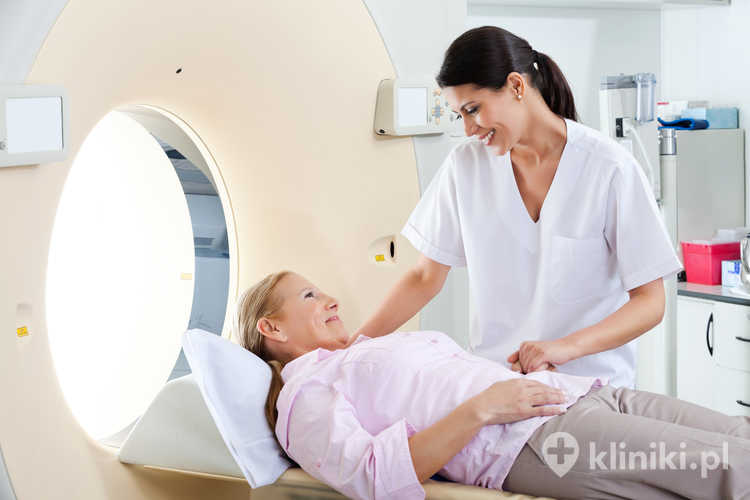 Technik radiolog uśmiecha się do dojrzałej pacjentki leżącej na łóżku do tomografii komputerowej