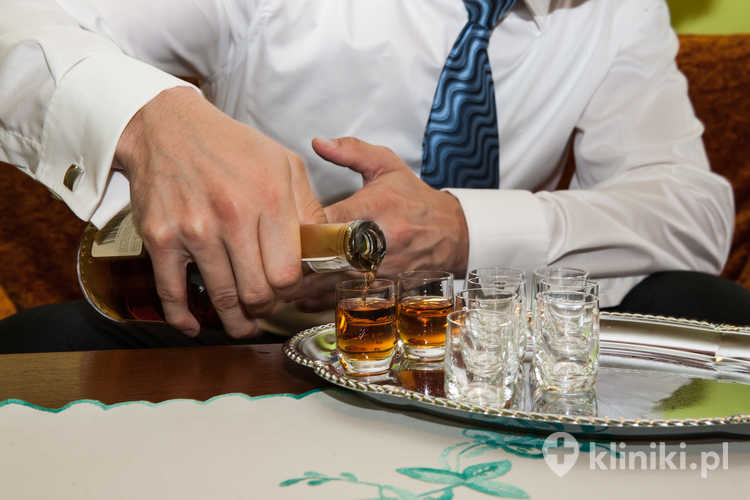 Alkoholik nalewa wódkę do kieliszków
