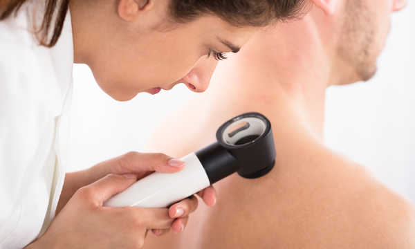 Lekarka badająca skórę pacjenta za pomocą dermatoskopu