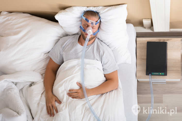 Młody mężczyzna leżący na łóżku z bezdechem sennym i maszyną CPAP