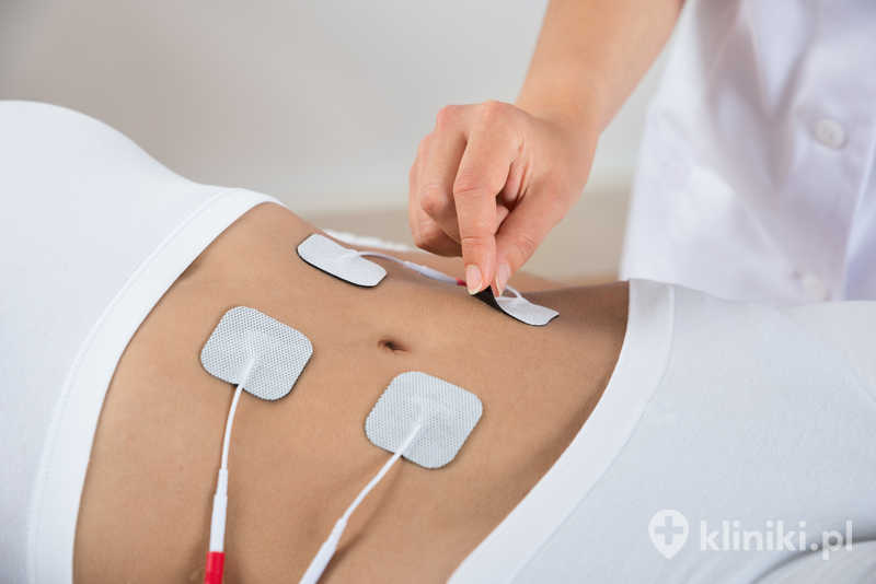 Terapeuta umieszcza elektrody na brzuchu kobiety