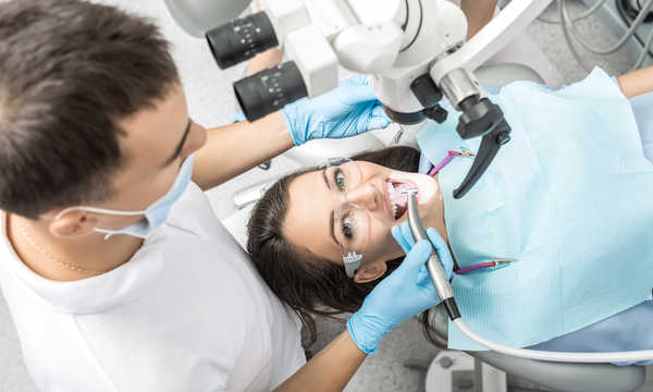 Pacjent w gabinecie dentystycznym. Mikroskop dentystyczny znajduje się nad pacjentem Pacjent w gabinecie dentystycznym. Mikroskop dentystyczny znajduje się nad pacjentem