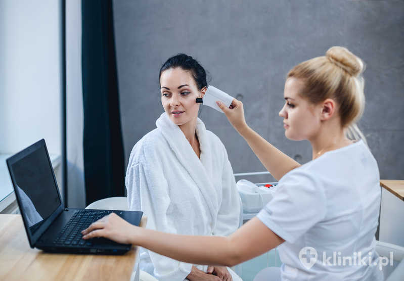 Lekarka i pacjentka podczas badania skóry twarzy. Wyniki stanu skóry są wyświetlane na laptopie