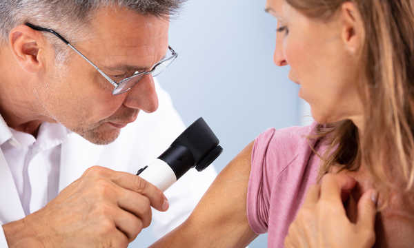 Lekarz sprawdza skórę pacjentki za pomocą dermatoskopu