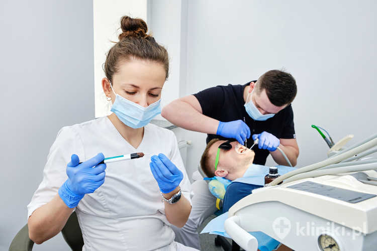 Dentysta i asystent cementujący korony. Zakładanie korony dentystycznej