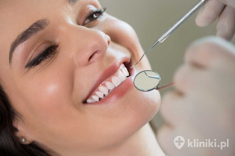 Zbliżenie dentysty badającego zęby młodej kobiety Zbliżenie dentysty badającego zęby młodej kobiety