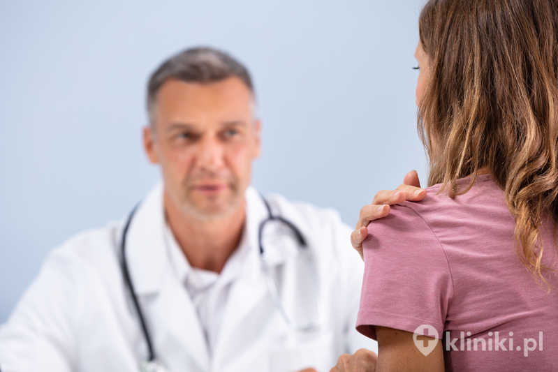 Kobieta pokazuje lekarzowi bolące ramię Kobieta pokazuje lekarzowi bolące ramię