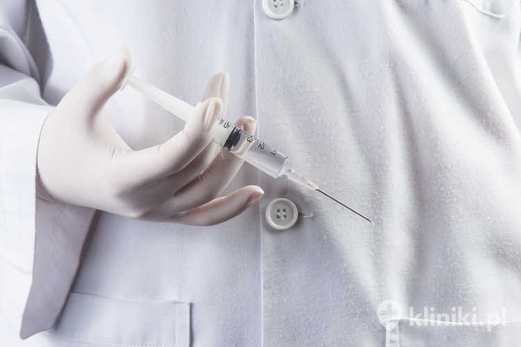 Lekarz lub pielęgniarka trzymający strzykawkę i przygotowujący się do zastrzyku