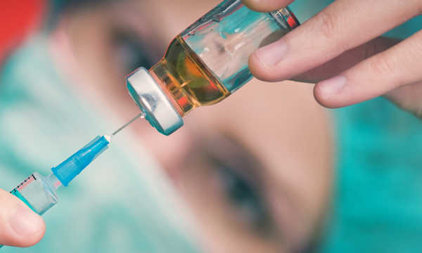 Lekarz trzymający strzykawkę i przygotowujący się do podania szczepionki