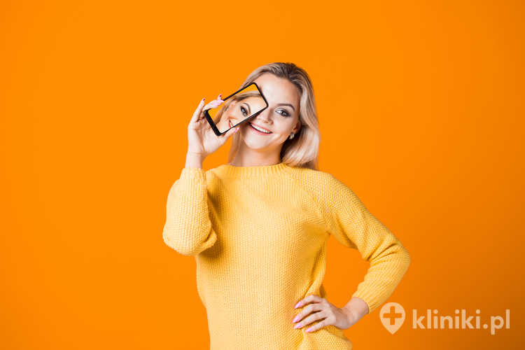 Portret dziewczyny korzystającej z telefonu komórkowego na żółtym tle