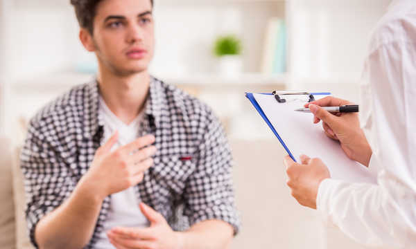 Psychoterapia. Mężczyzna z depresją rozmawia z terapeutką, która robi notatki.