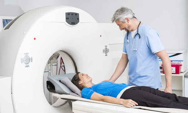 Uśmiechnięty lekarz rozmawia z pacjentką leżącą na stole tomografu komputerowego w szpitalu Uśmiechnięty lekarz rozmawia z pacjentką leżącą na stole tomografu komputerowego w szpitalu
