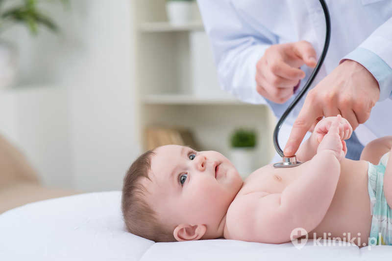 Zaangażowany w swoją pracę pediatra bada niemowlę, trzymając stetoskop Zaangażowany w swoją pracę pediatra bada niemowlę, trzymając stetoskop