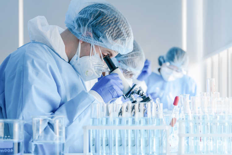 Zespół naukowców-biochemików pracujący z mikroskopem nad opracowaniem szczepionki