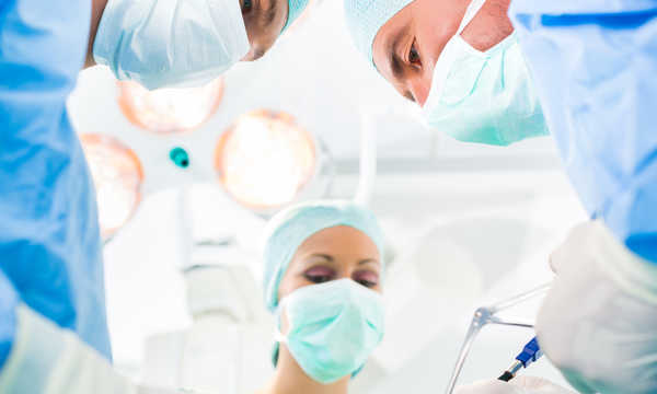 Zespół chirurgów na sali operacyjnej w trakcie liposukcji klatki piersiowej u mężczyzny